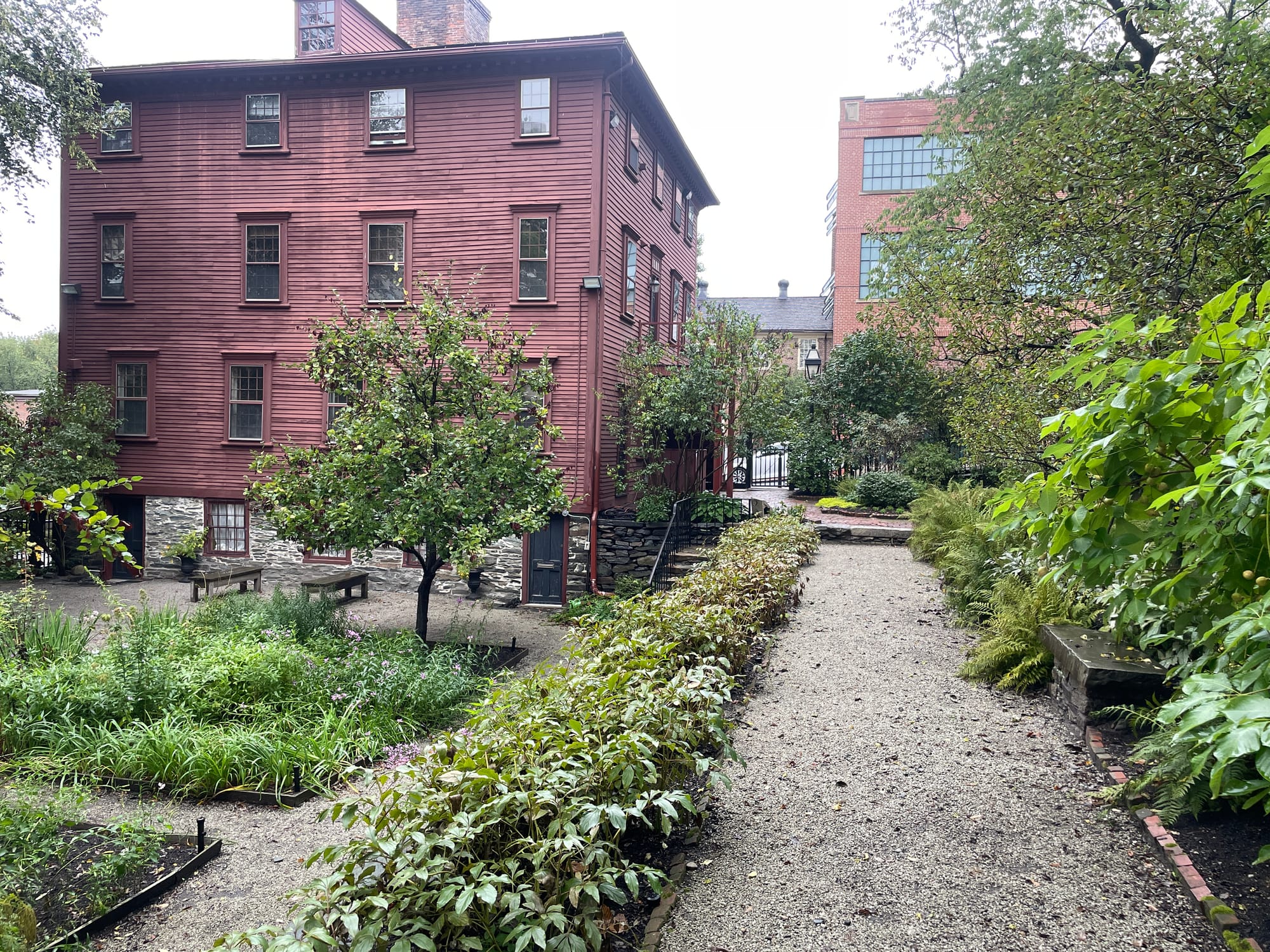 A historic deep-red clapboard house down a garden path